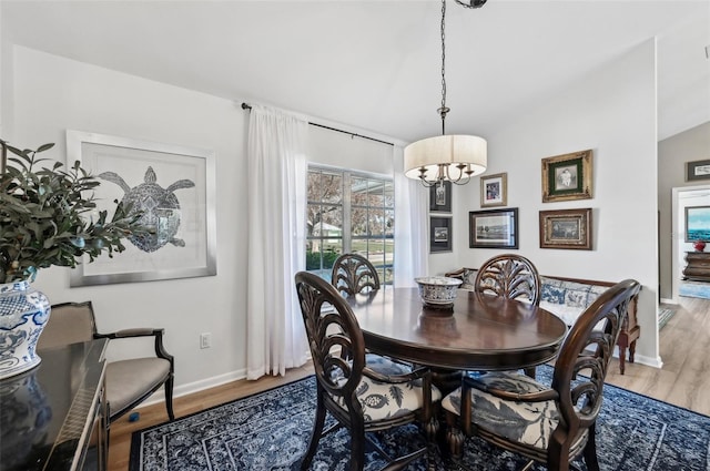 dining area with hardwood / wood-style flooring, lofted ceiling, and a chandelier