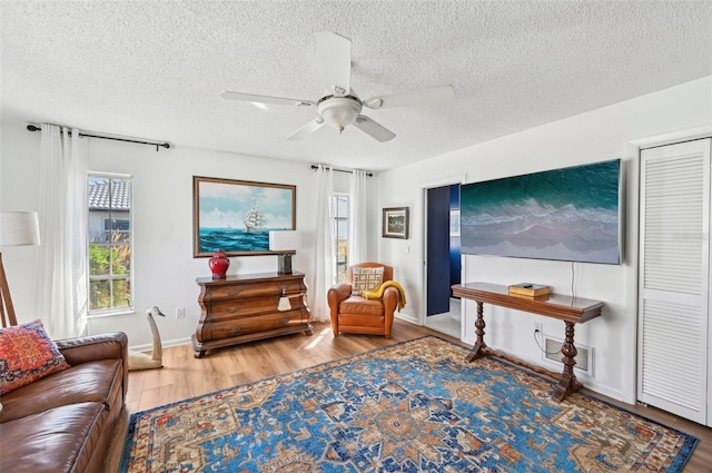 living area featuring hardwood / wood-style floors, a textured ceiling, and ceiling fan