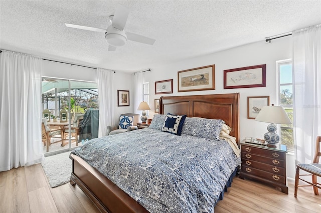 bedroom featuring light hardwood / wood-style floors, access to outside, multiple windows, and ceiling fan