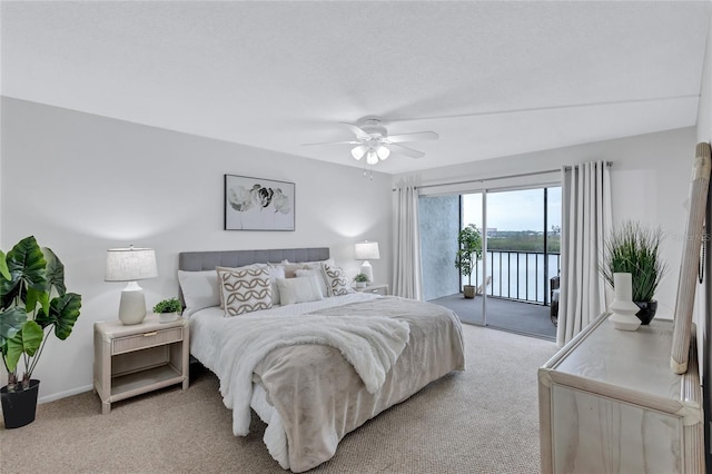 carpeted bedroom with a water view, ceiling fan, and access to exterior