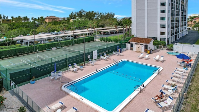 view of swimming pool featuring a patio and tennis court