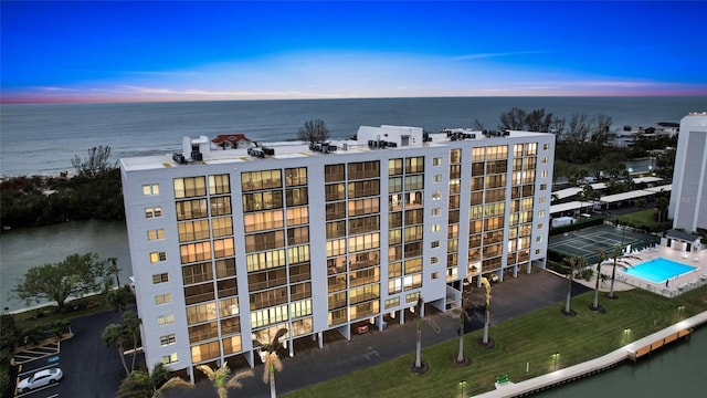 outdoor building at dusk featuring a water view and a community pool