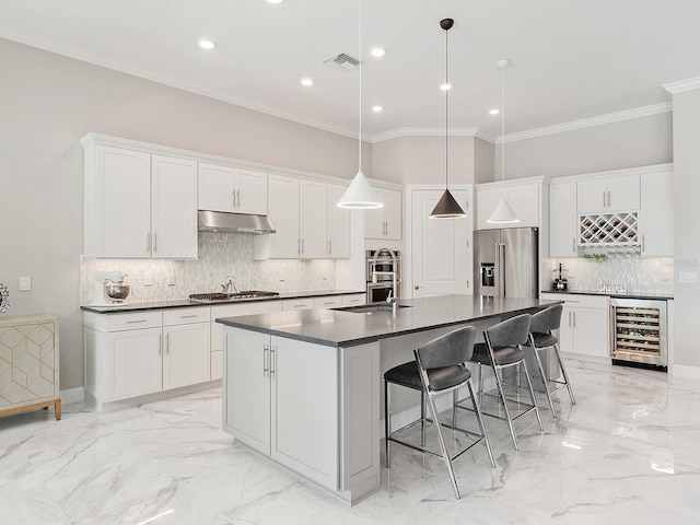 kitchen with pendant lighting, a center island with sink, wine cooler, appliances with stainless steel finishes, and white cabinetry