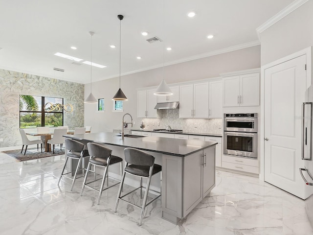 kitchen featuring white cabinetry, sink, hanging light fixtures, a center island with sink, and appliances with stainless steel finishes