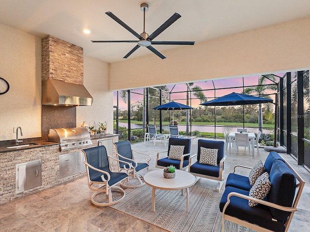 patio terrace at dusk with an outdoor hangout area, area for grilling, a lanai, sink, and exterior kitchen