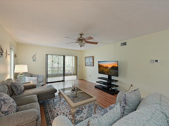 living room featuring hardwood / wood-style floors, a textured ceiling, and ceiling fan