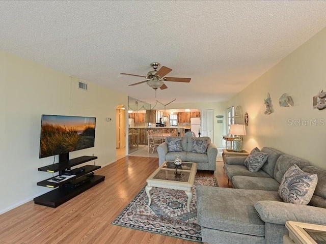 living room with a textured ceiling, hardwood / wood-style flooring, and ceiling fan