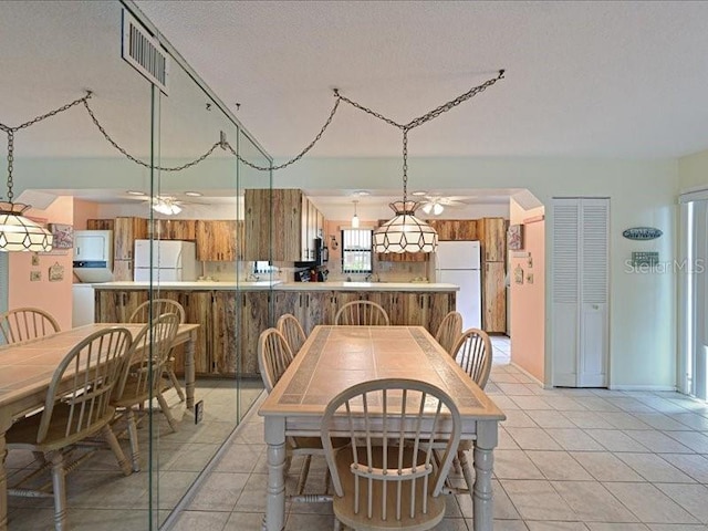 dining space featuring ceiling fan, a textured ceiling, and light tile patterned floors