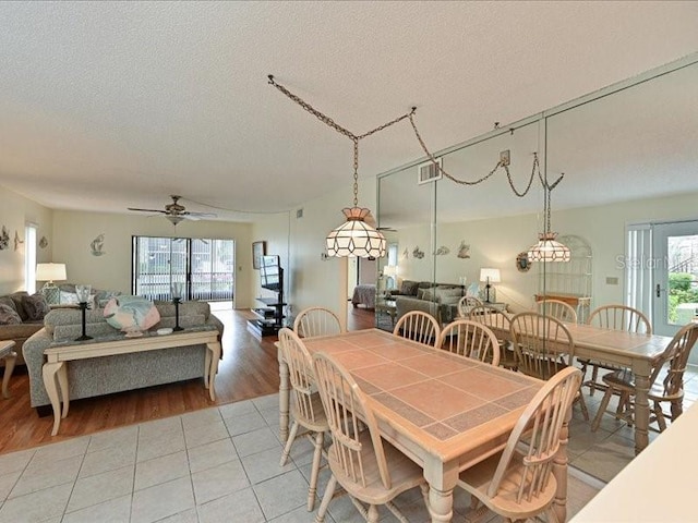 dining space with light hardwood / wood-style floors, a textured ceiling, ceiling fan, and a wealth of natural light