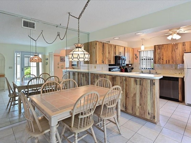 dining area with sink, ceiling fan, a textured ceiling, and light tile patterned floors