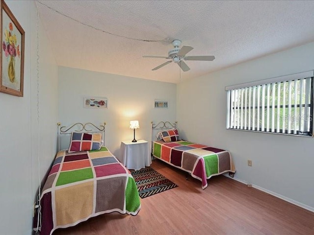 bedroom with ceiling fan, wood-type flooring, and a textured ceiling