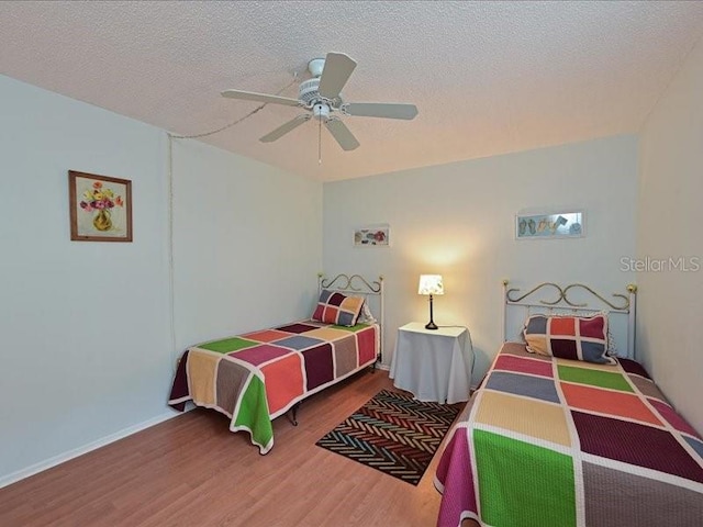 bedroom featuring hardwood / wood-style floors, a textured ceiling, and ceiling fan