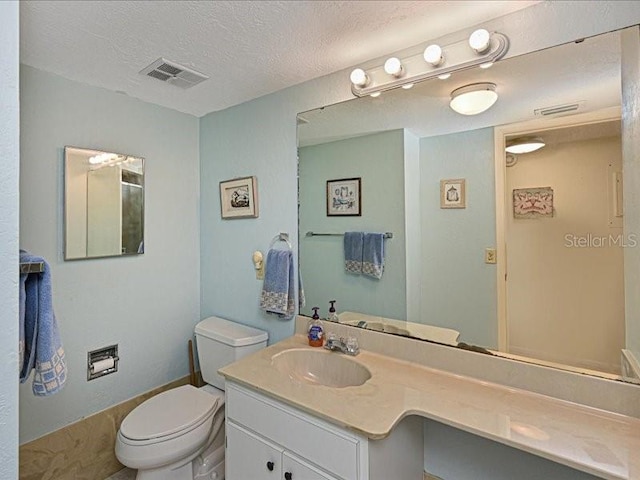 bathroom with vanity, toilet, and a textured ceiling