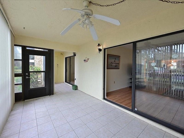 unfurnished sunroom featuring ceiling fan