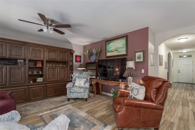 living room featuring ceiling fan, a textured ceiling, and light hardwood / wood-style flooring