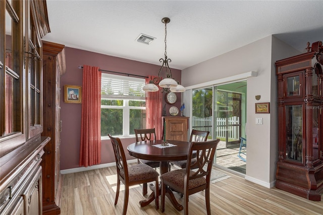 dining area with a textured ceiling, a chandelier, and light wood-type flooring