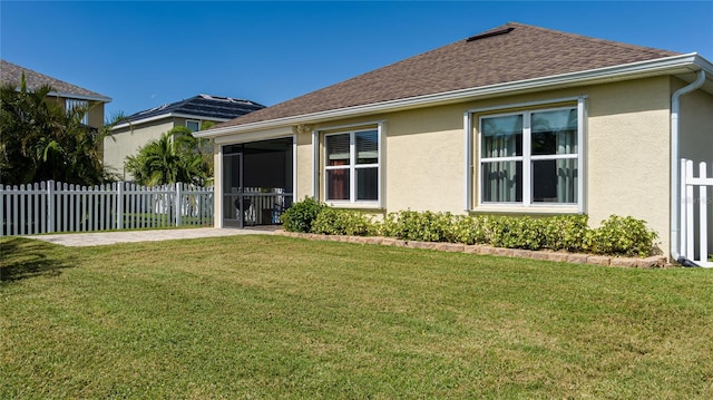 rear view of house with a yard and a sunroom