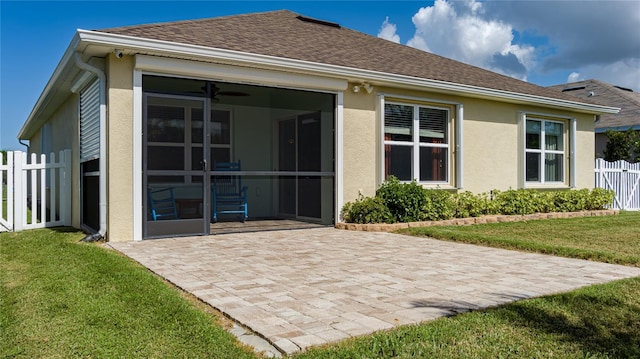 back of house featuring a patio area, a sunroom, a lawn, and ceiling fan