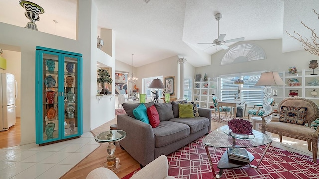 living room featuring a textured ceiling, high vaulted ceiling, tile patterned floors, and ceiling fan with notable chandelier