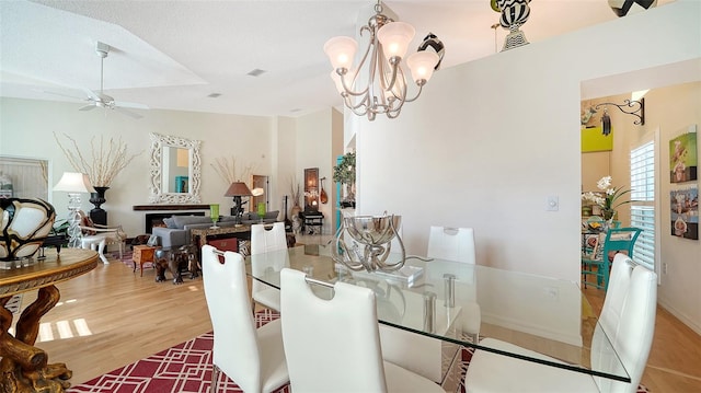 dining area with a textured ceiling, vaulted ceiling, hardwood / wood-style flooring, and ceiling fan with notable chandelier