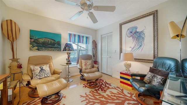 sitting room with hardwood / wood-style floors and ceiling fan