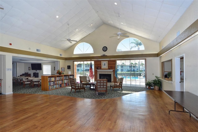 living room with hardwood / wood-style floors, high vaulted ceiling, a tile fireplace, and ceiling fan