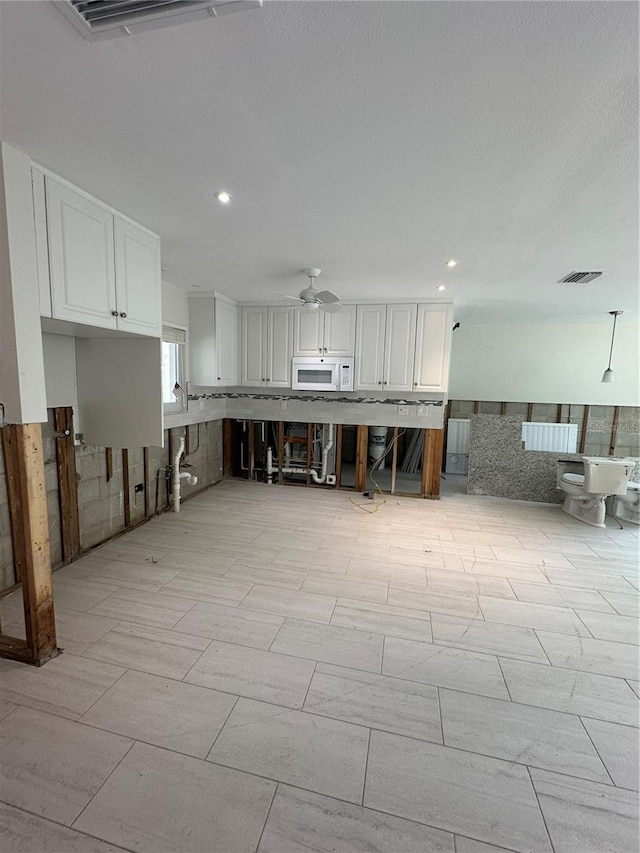 kitchen with ceiling fan and white cabinets