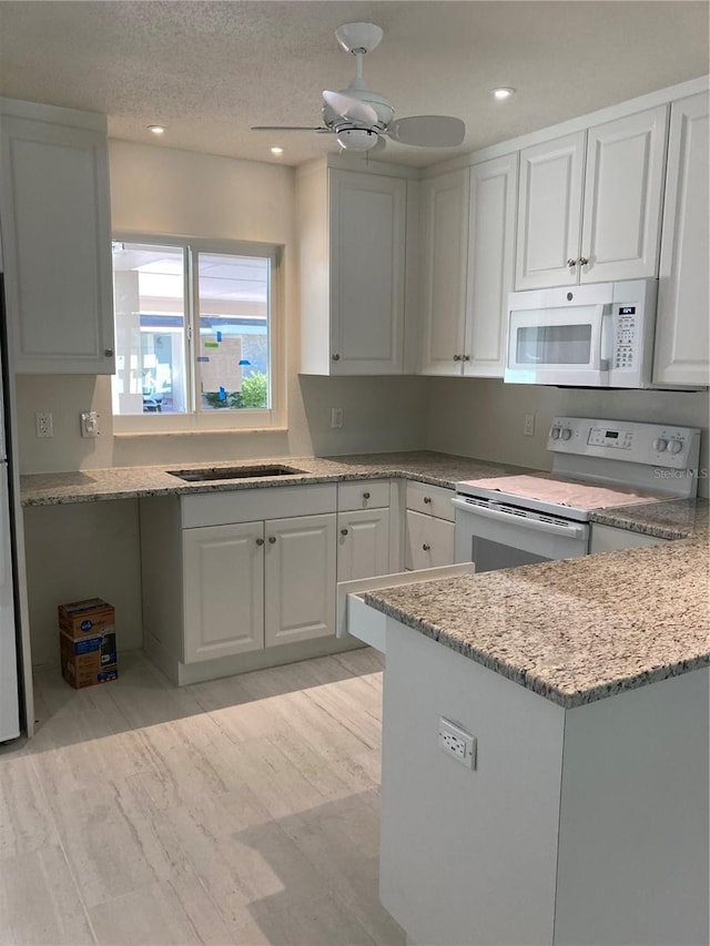 kitchen with light hardwood / wood-style floors, light stone countertops, ceiling fan, white appliances, and white cabinets