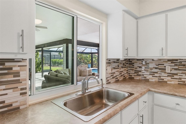 kitchen featuring ceiling fan, tasteful backsplash, sink, and white cabinets