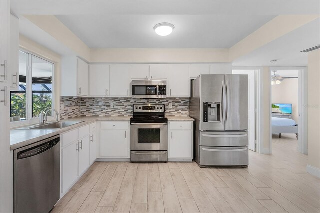 kitchen featuring appliances with stainless steel finishes, white cabinets, sink, and light wood-type flooring