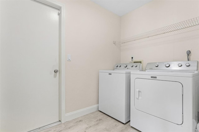 laundry area featuring washing machine and dryer and light hardwood / wood-style flooring