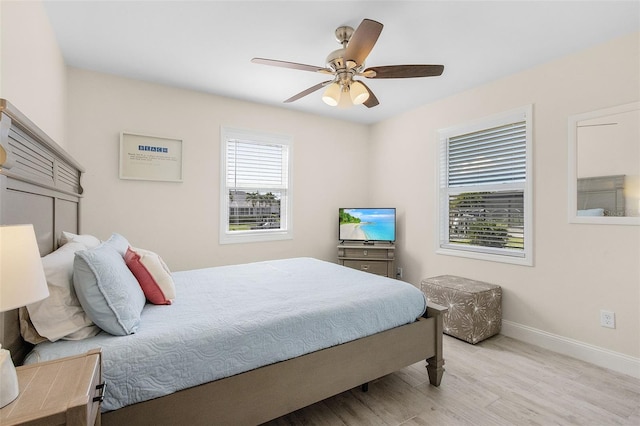 bedroom featuring ceiling fan, multiple windows, and light wood-type flooring