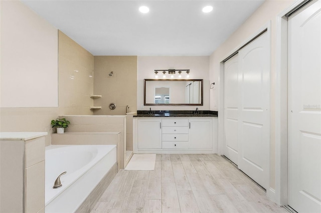 bathroom with vanity, a tub to relax in, and hardwood / wood-style flooring