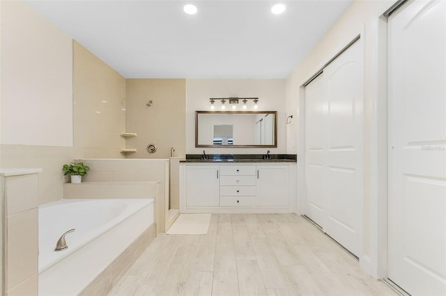 bathroom featuring vanity, a tub to relax in, and wood-type flooring