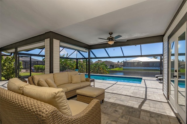 view of pool with outdoor lounge area, a patio area, a water view, glass enclosure, and ceiling fan