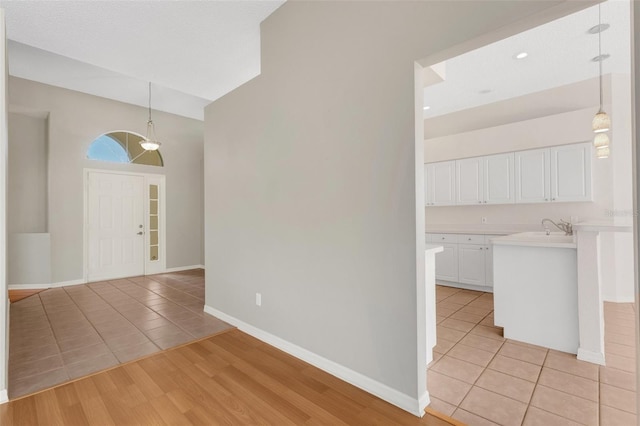 entrance foyer with lofted ceiling, sink, light hardwood / wood-style flooring, and a textured ceiling