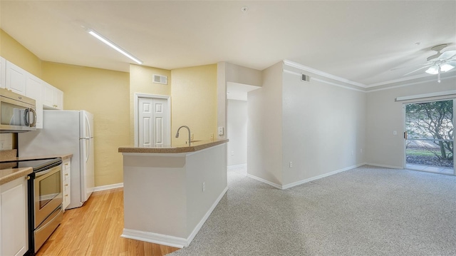 kitchen with appliances with stainless steel finishes, light wood-type flooring, white cabinetry, and ceiling fan