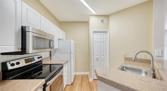 kitchen featuring black electric range, sink, light wood-type flooring, white cabinetry, and decorative backsplash