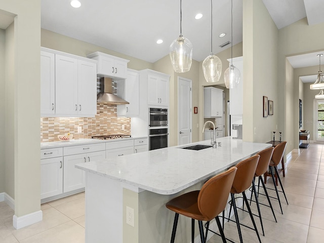 kitchen featuring decorative backsplash, wall chimney range hood, sink, and decorative light fixtures