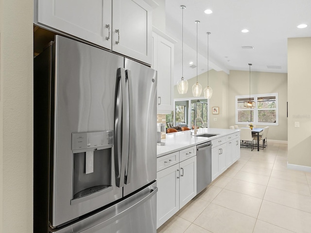 kitchen with sink, vaulted ceiling with beams, decorative light fixtures, white cabinets, and appliances with stainless steel finishes