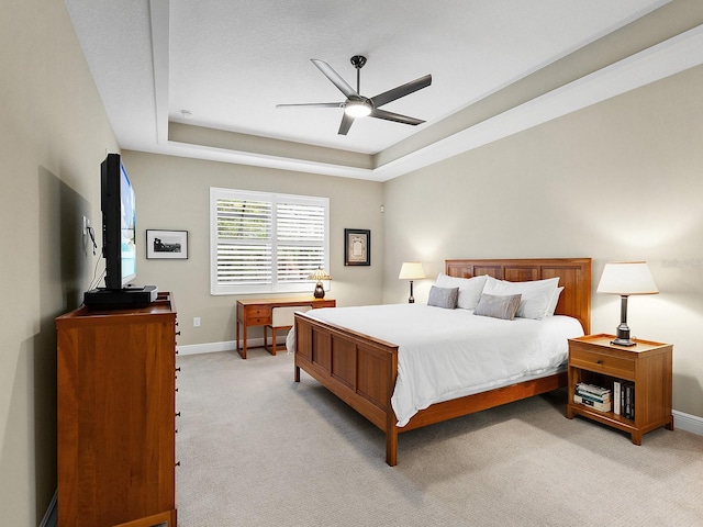 carpeted bedroom with ceiling fan and a raised ceiling