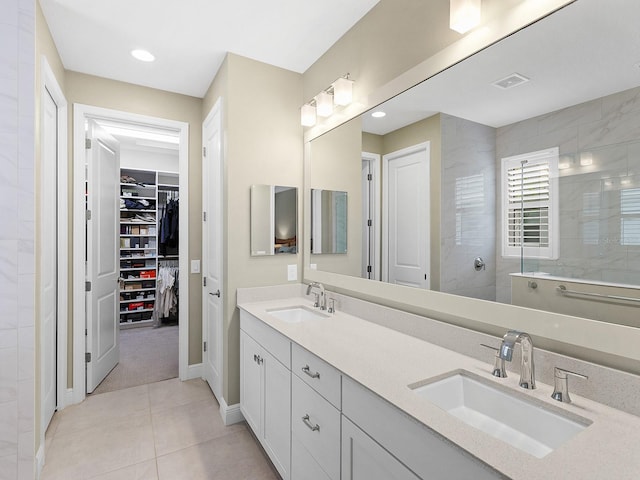 bathroom featuring tile patterned flooring, a tile shower, and vanity