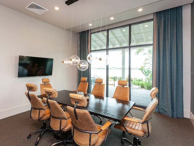 dining room with dark colored carpet and a wall of windows