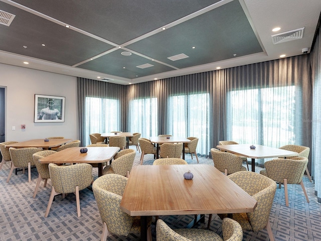 dining room featuring carpet flooring, a healthy amount of sunlight, and a raised ceiling