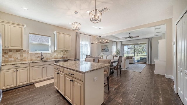 kitchen featuring sink, a kitchen island, hanging light fixtures, and dark wood-type flooring