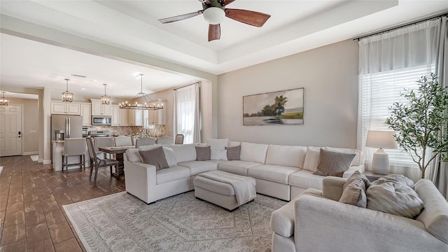 living room featuring dark wood-type flooring and ceiling fan with notable chandelier