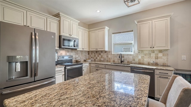 kitchen featuring light stone countertops, sink, appliances with stainless steel finishes, and backsplash