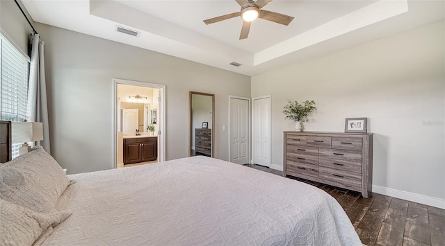 bedroom with a raised ceiling, ceiling fan, dark wood-type flooring, ensuite bath, and sink