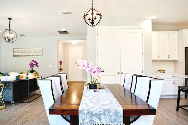 dining room with light hardwood / wood-style floors and a chandelier