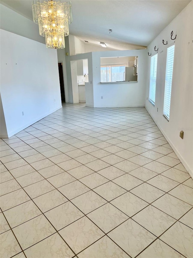 tiled spare room featuring a notable chandelier and vaulted ceiling